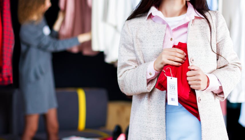 Woman shoplifting a pair of red pants in a boutique 