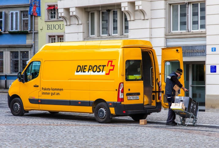 Lastwagen-Van der Schweizerischen Post mit Postangestellten bei der Ausslieferung von Paketen