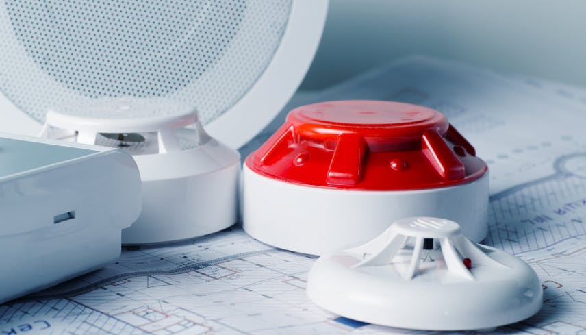 Smoke detectors and fire alarm panels on paperwork
