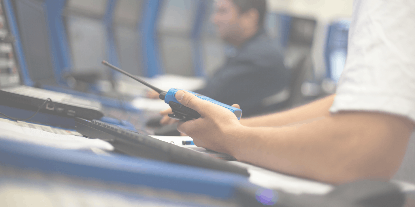 Close up of an operator holding a walkie talkie in a control center