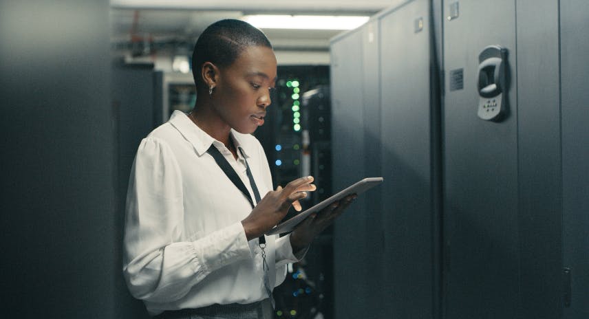 Eine junge Frau benutzt ein digitales Tablet bei der Arbeit in einem Data Center
