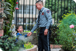 Ein Latino-Junge verlässt sein Haus, um den Wachmann zu begrüßen, der für die Sicherheit der Gemeinde zuständig ist.