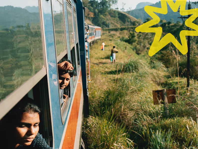 Niños mirando por la ventanilla de un tren en marcha en Sri Lanka
