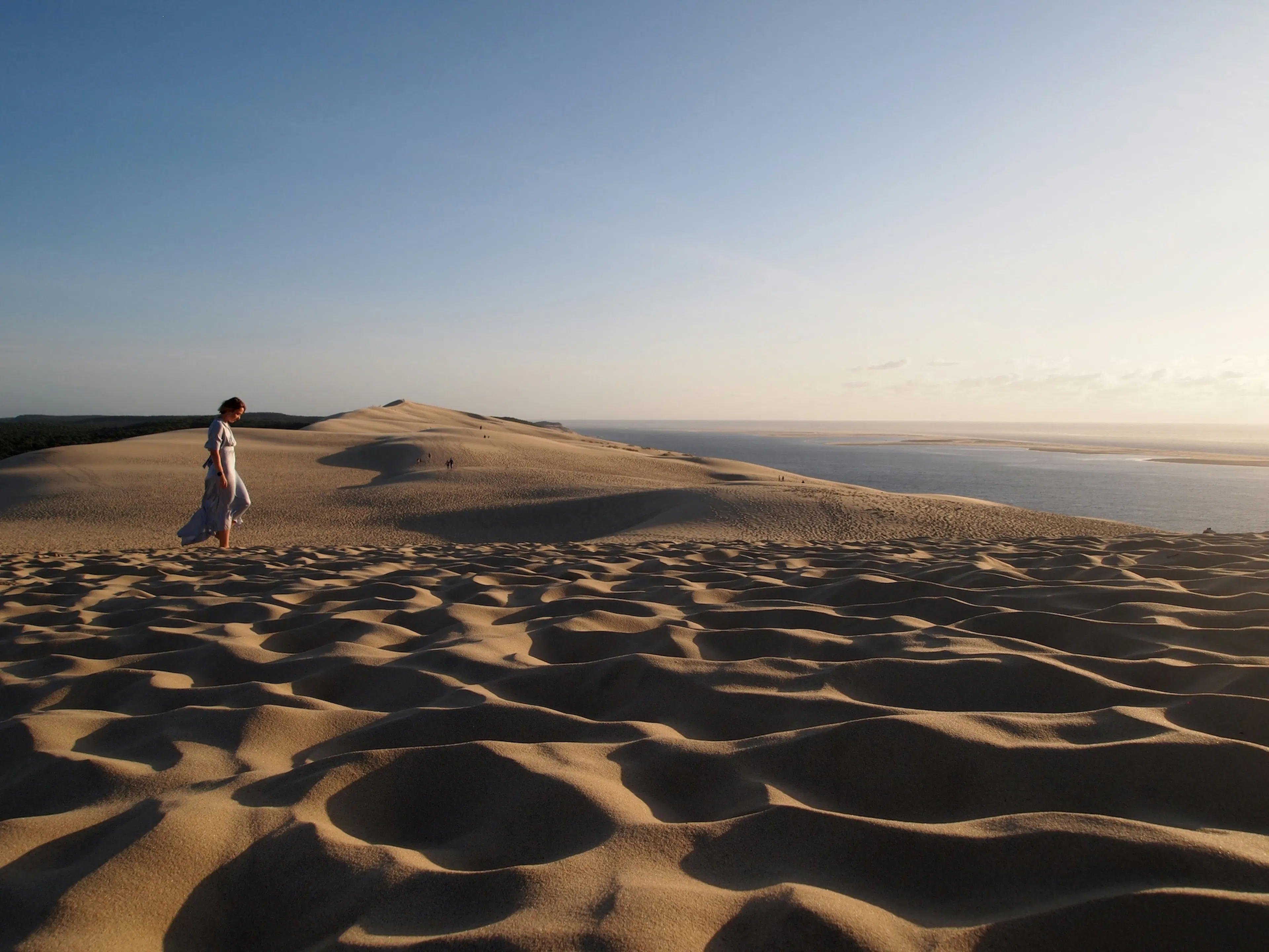 Une femme marchant sur la dune du Pilat dans le Sud Ouest un soir d'été