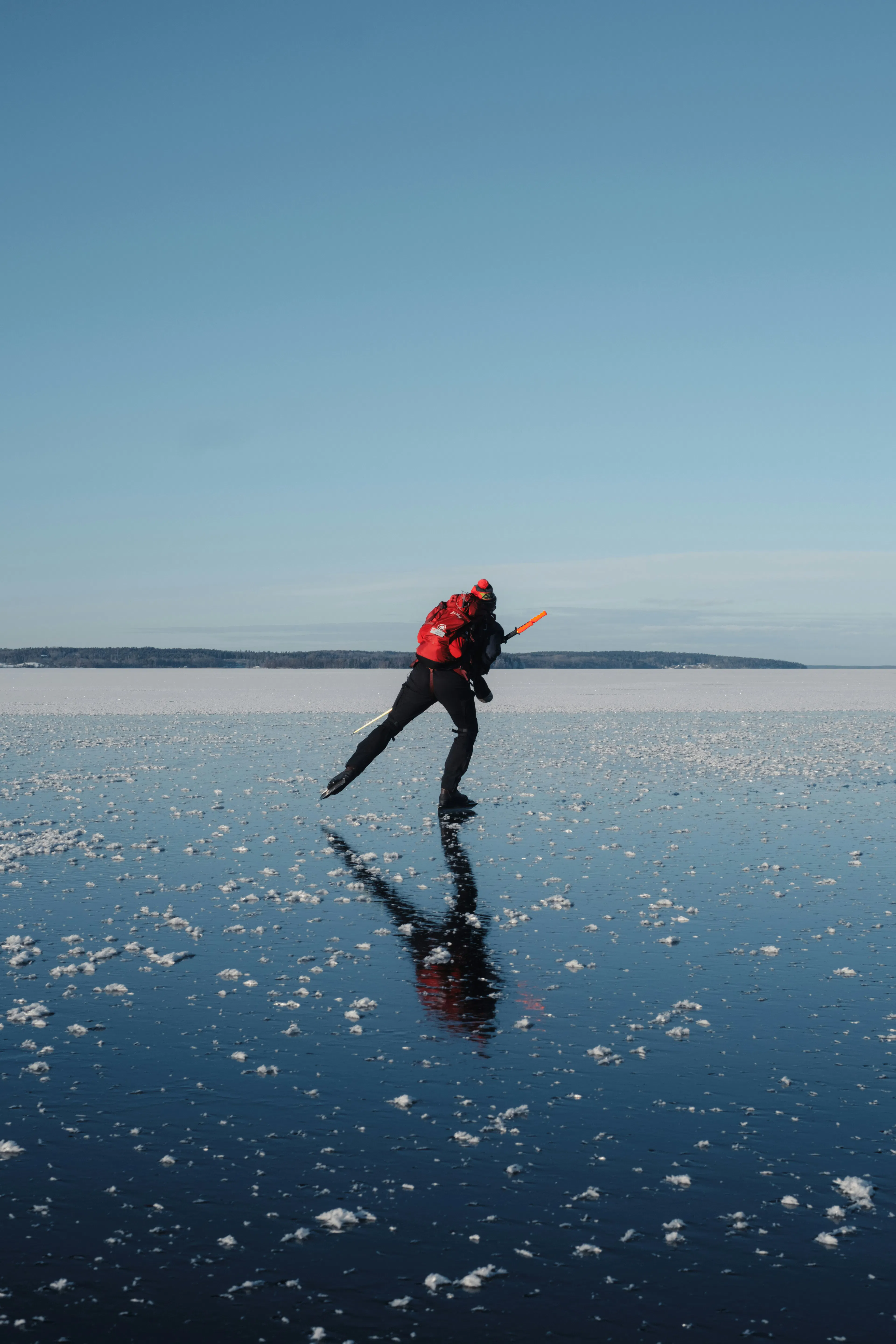 Un homme patinant sur un lac gelé à la glace cristalline, en Suède