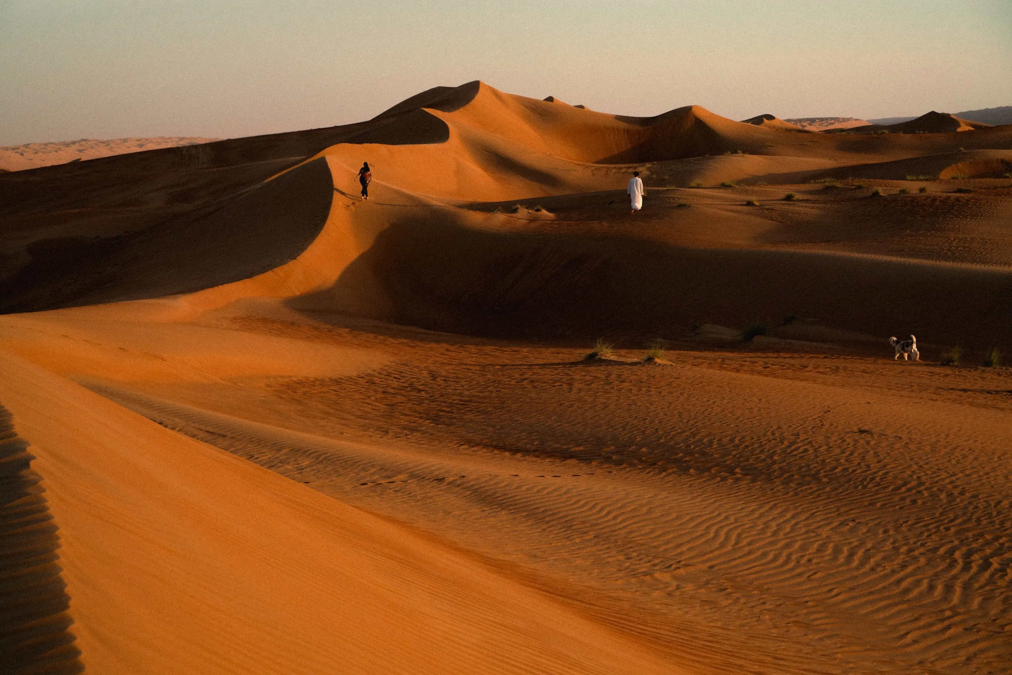 Un homme debout au milieu d'un désert aux teintes rouges et brunes à Oman
