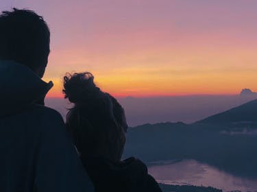 Couple admirant le lever du soleil face au mont Batur en Indonésie