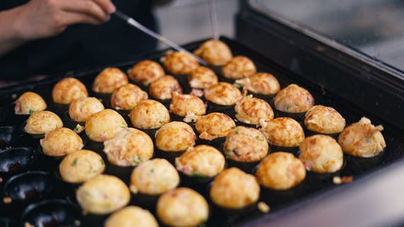 Cuisinier retournant des Takoyaki dans leur moule