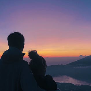 Couple admirant le lever du soleil face au mont Batur en Indonésie