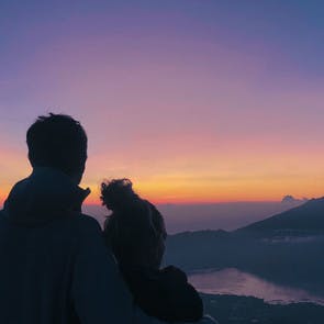Couple admirant le lever du soleil face au mont Batur en Indonésie