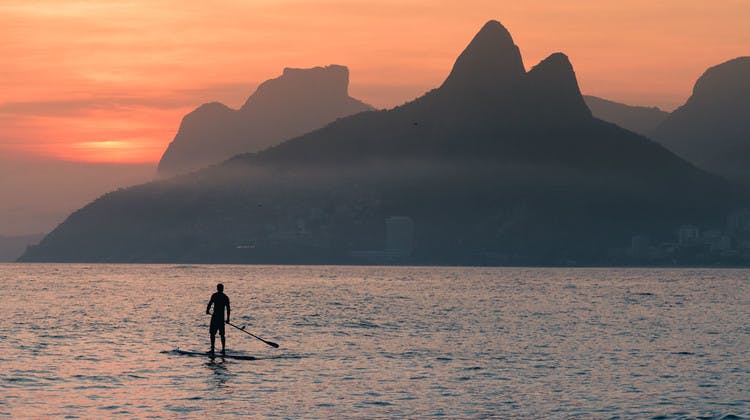 Silhouette d'un homme sur un paddle au large de la plage d'Arpoador