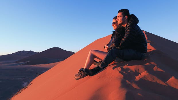 Couple admirant le lever du soleil sur les dunes de Namibie