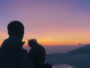 Couple admirant le lever du soleil face au mont Batur en Indonésie