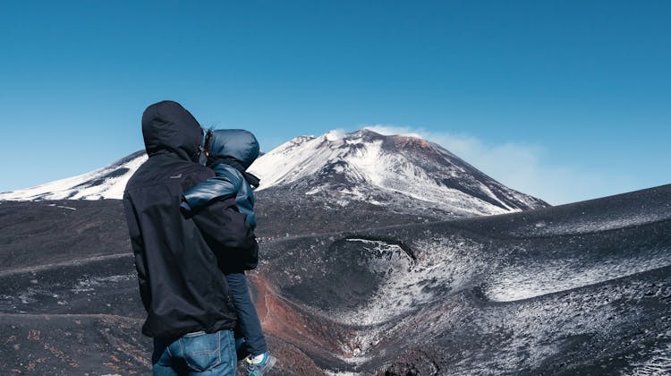Un homme et son enfant face à l'Etna en Sicile
