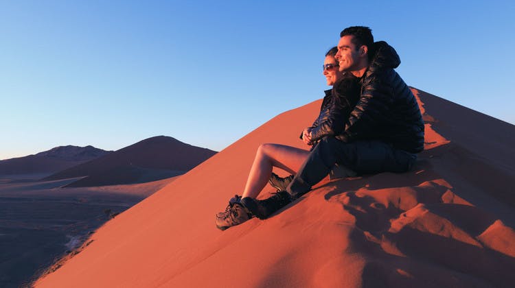 Couple admirant le lever du soleil sur les dunes de Namibie