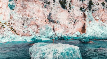 Frau steht auf blauem Felsen vor Sardinien im Golf von Orosei