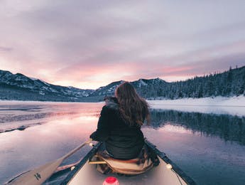 Jeune femme de dos sur un canoë au milieu d'un lac