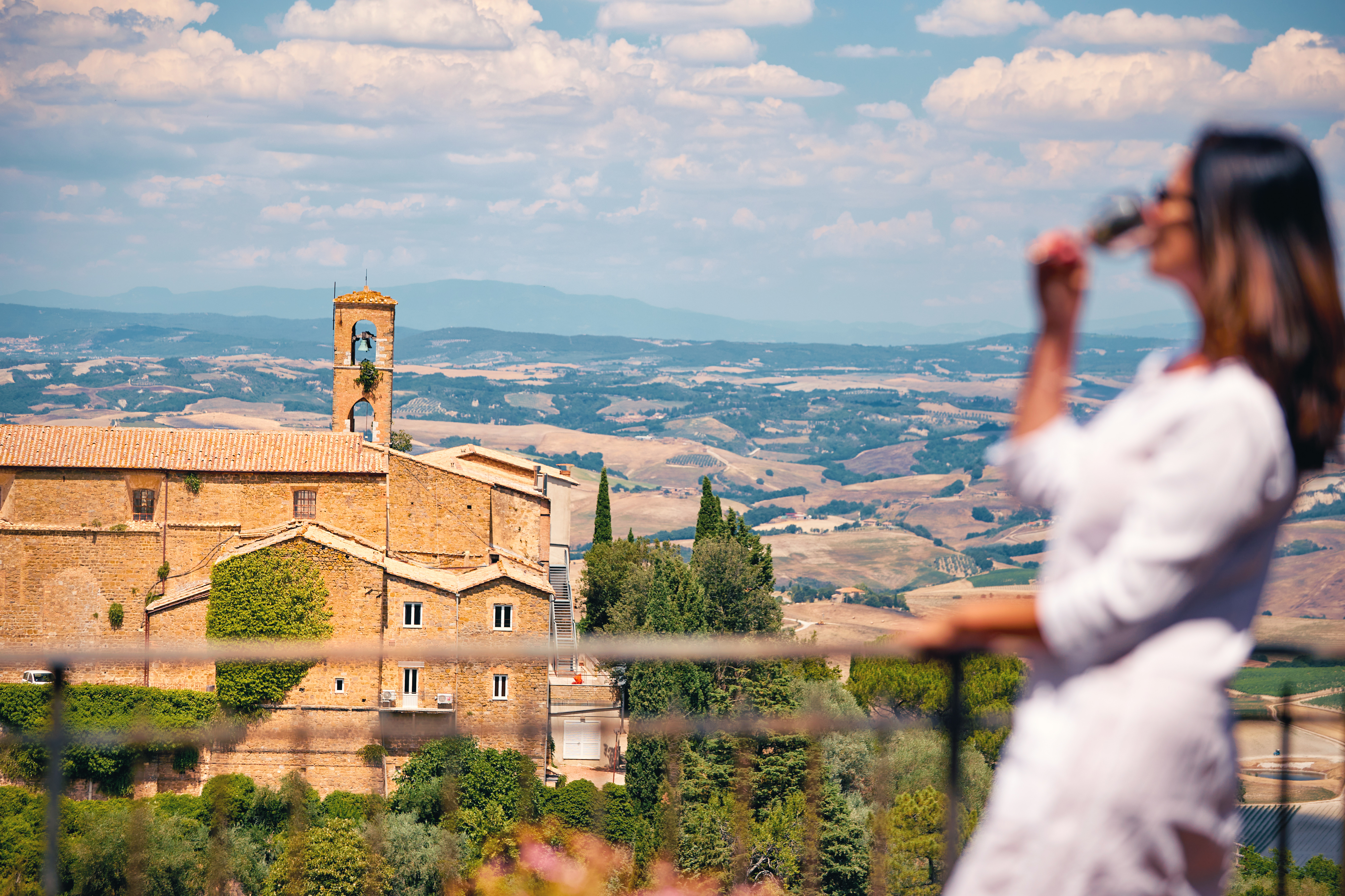 Frau blickt vom Balkon auf die toskanische Landschaft