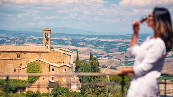 Frau blickt vom Balkon auf die toskanische Landschaft