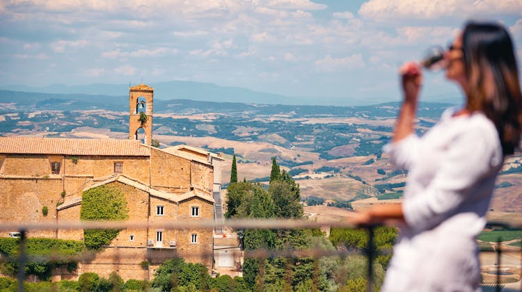 Frau blickt vom Balkon auf die toskanische Landschaft