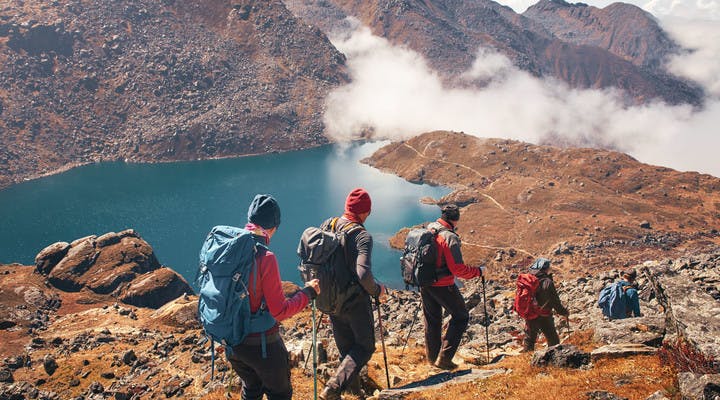 Groupe de randonneurs en montagne se dirigeant vers un lac