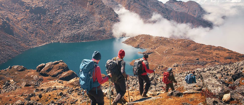 Groupe de randonneurs en montagne se dirigeant vers un lac