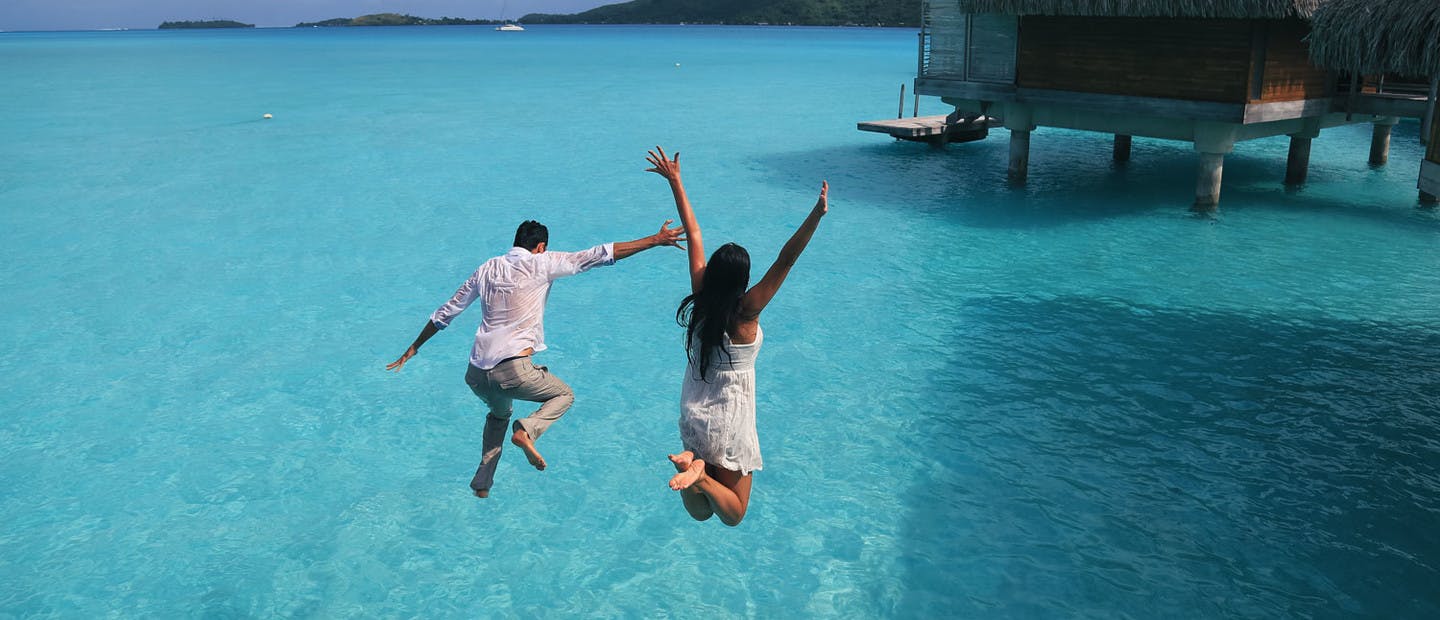 Couple sautant dans un lagon