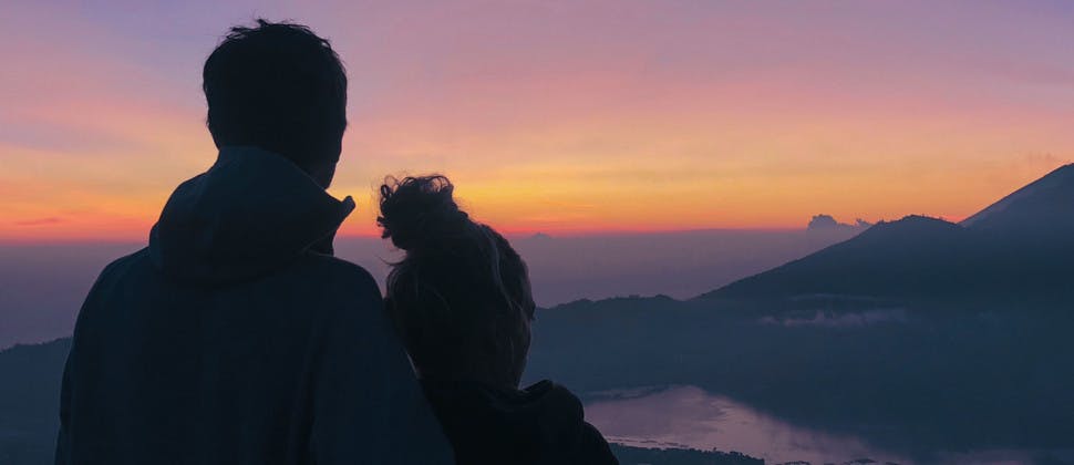 Couple admirant le lever du soleil face au mont Batur en Indonésie