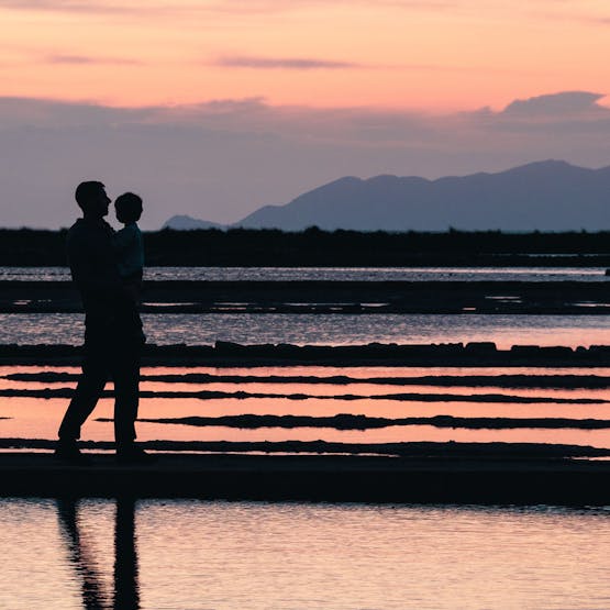 Un homme et son enfant devant les marais salants à Trapani