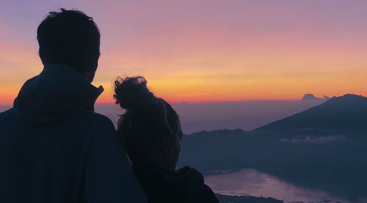 Couple admirant le lever du soleil face au mont Batur en Indonésie