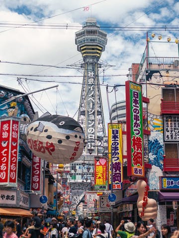 Rue bondée du quartier de Shinsekai avec la tour Tsûtenkaku en fond