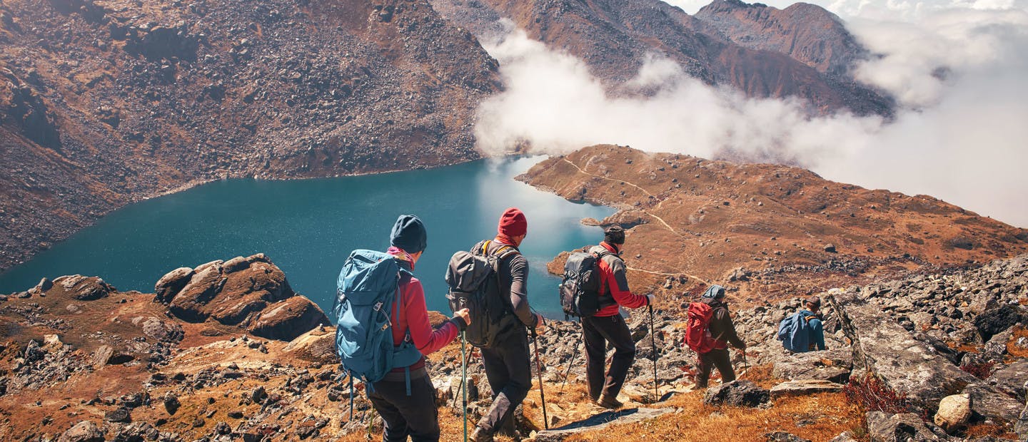 Groupe de randonneurs en montagne se dirigeant vers un lac