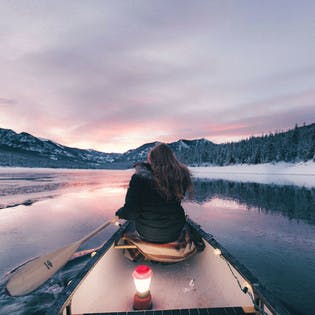 Jeune femme de dos sur un canoë au milieu d'un lac