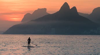 Silhouette d'un homme sur un paddle au large de la plage d'Arpoador