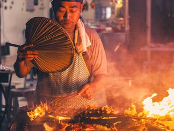 Un homme grillant des brochettes en Malaisie