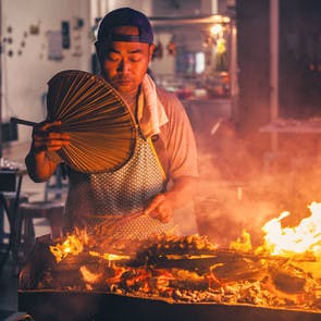 Un homme grillant des brochettes en Malaisie