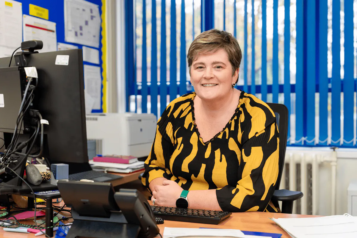 School administrator sitting at her desk and smiling