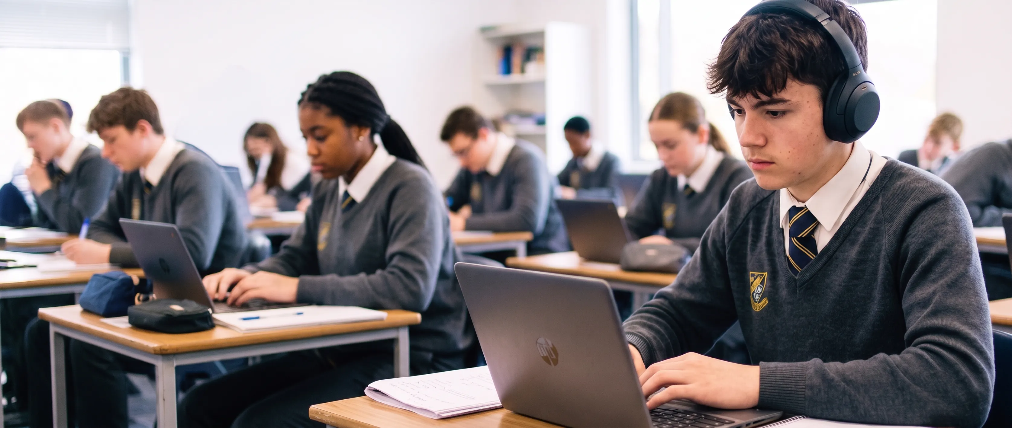 Students in a classroom using laptops to complete an exam.