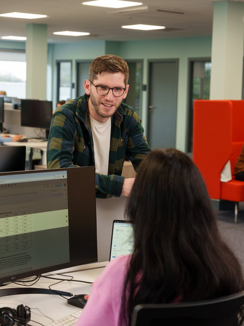 Two office employees are chatting, one is using Read&Write screen masking on their computer