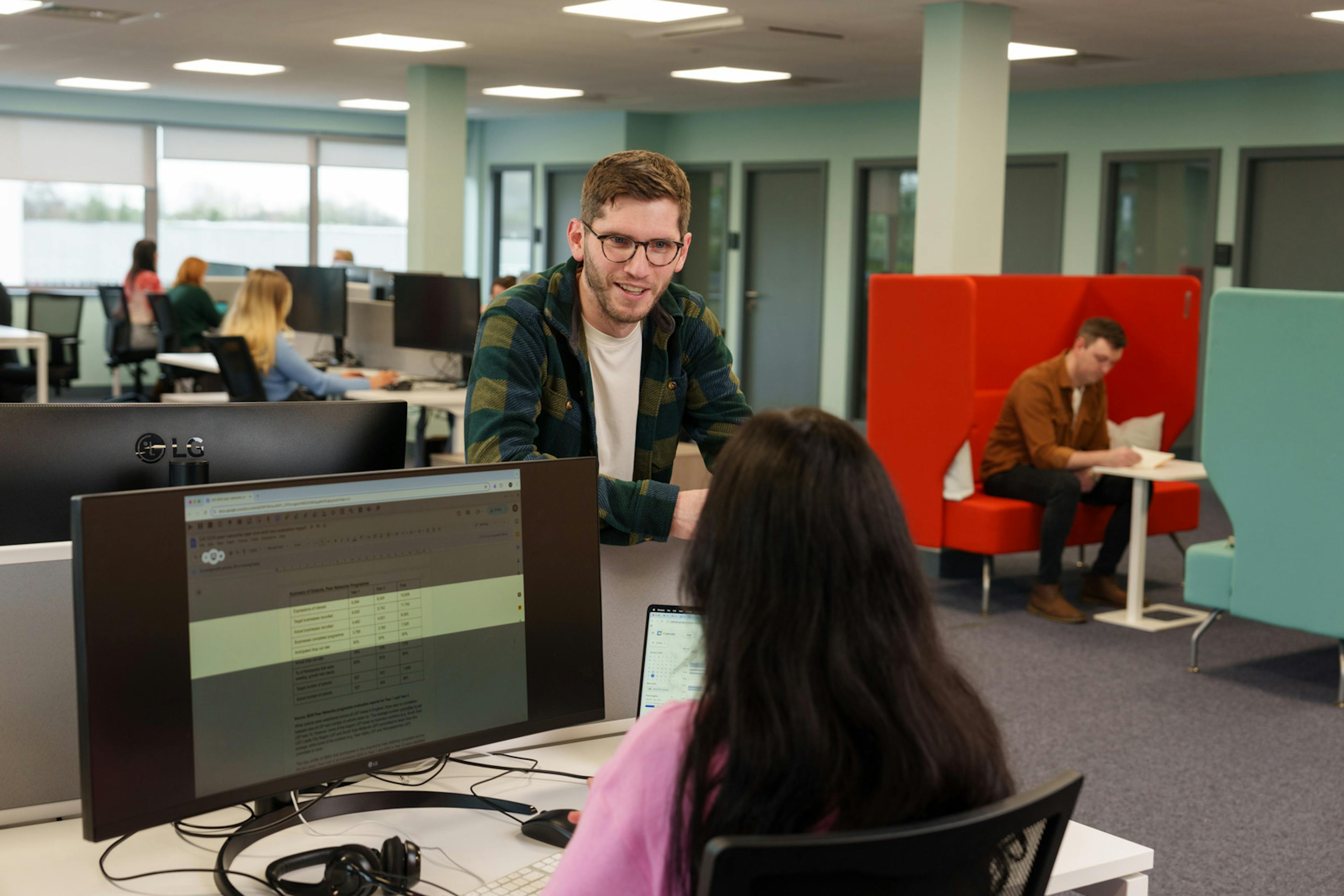 Two office employees are chatting, one is using Read&Write screen masking on their computer