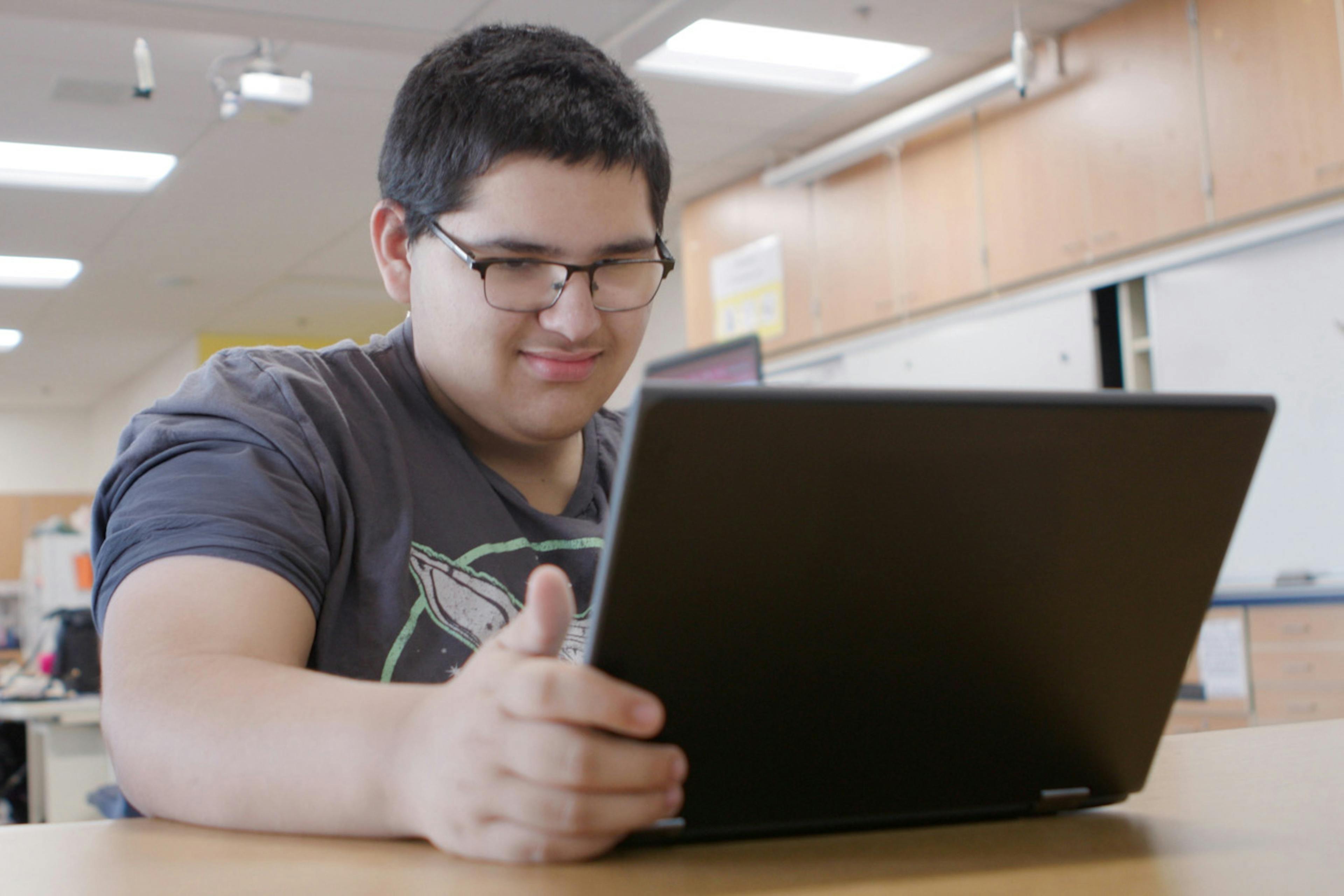 A student in a classroom using a tablet device