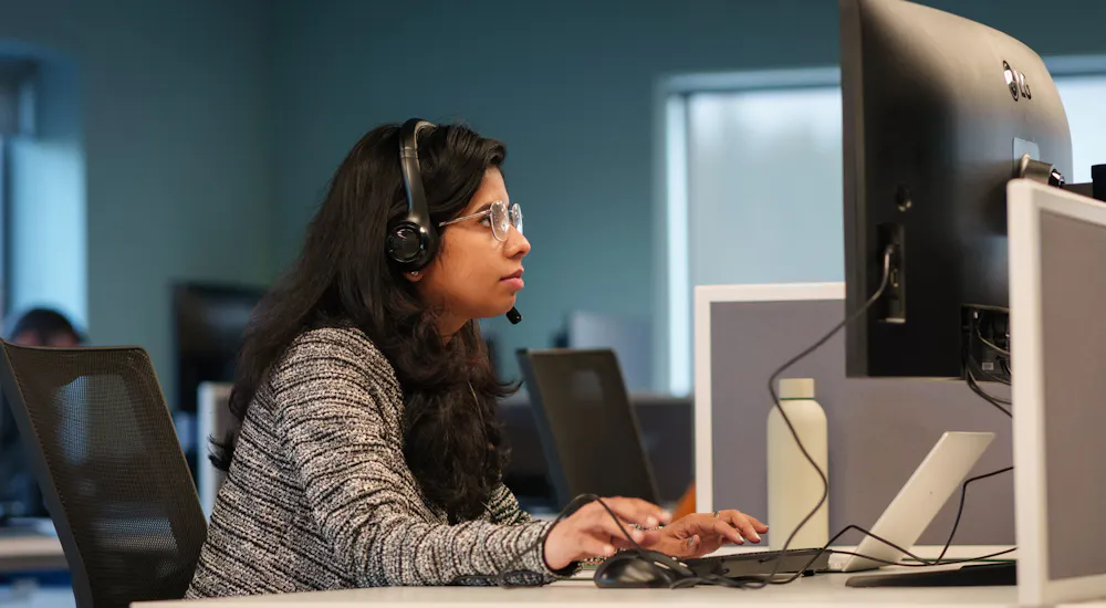 An employee at a computer with headphones