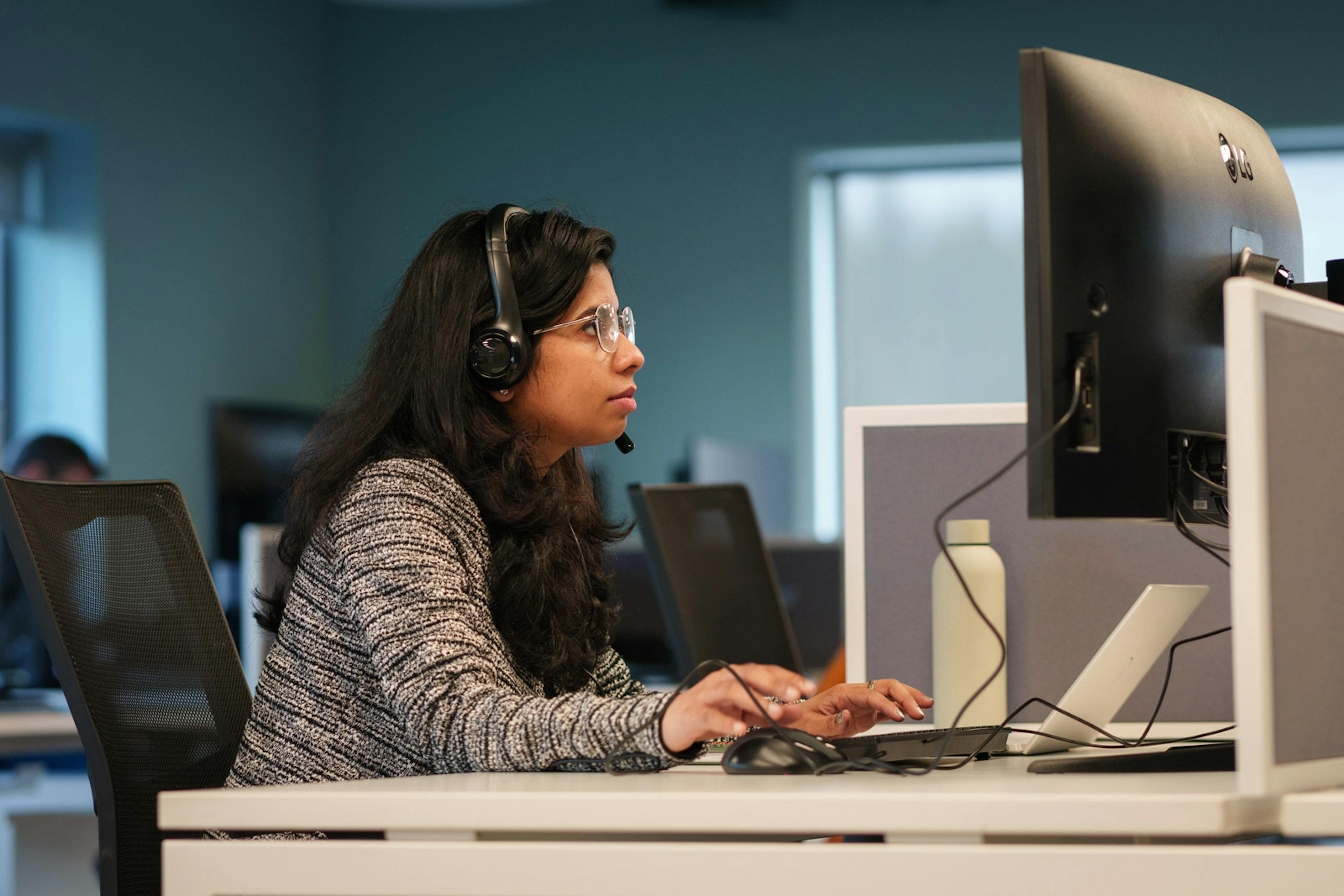 An employee at a computer with headphones