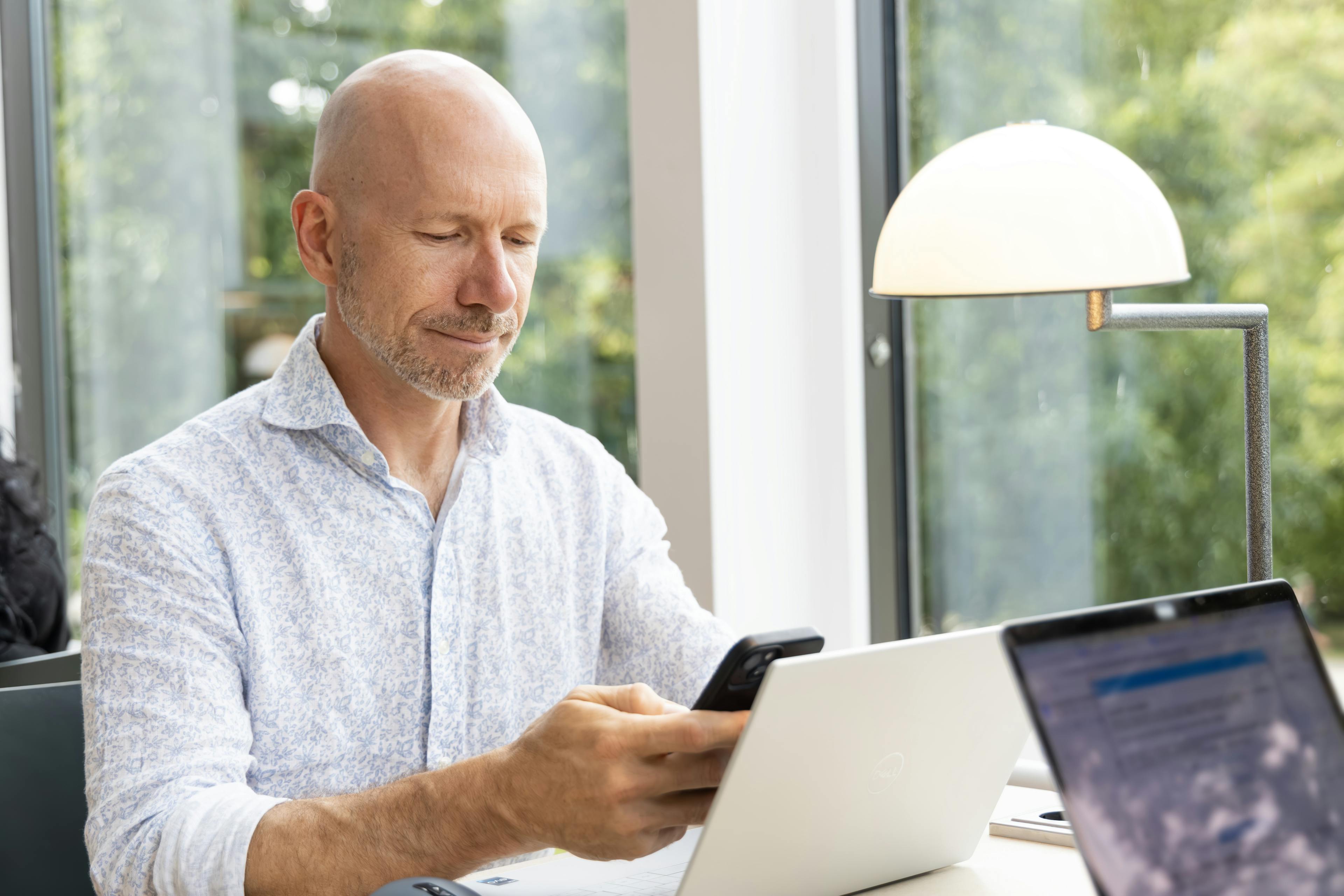 An individual with a laptop looking at their phone