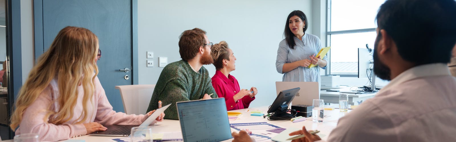 A group of people in a meeting space looking towards the person leading the meeting