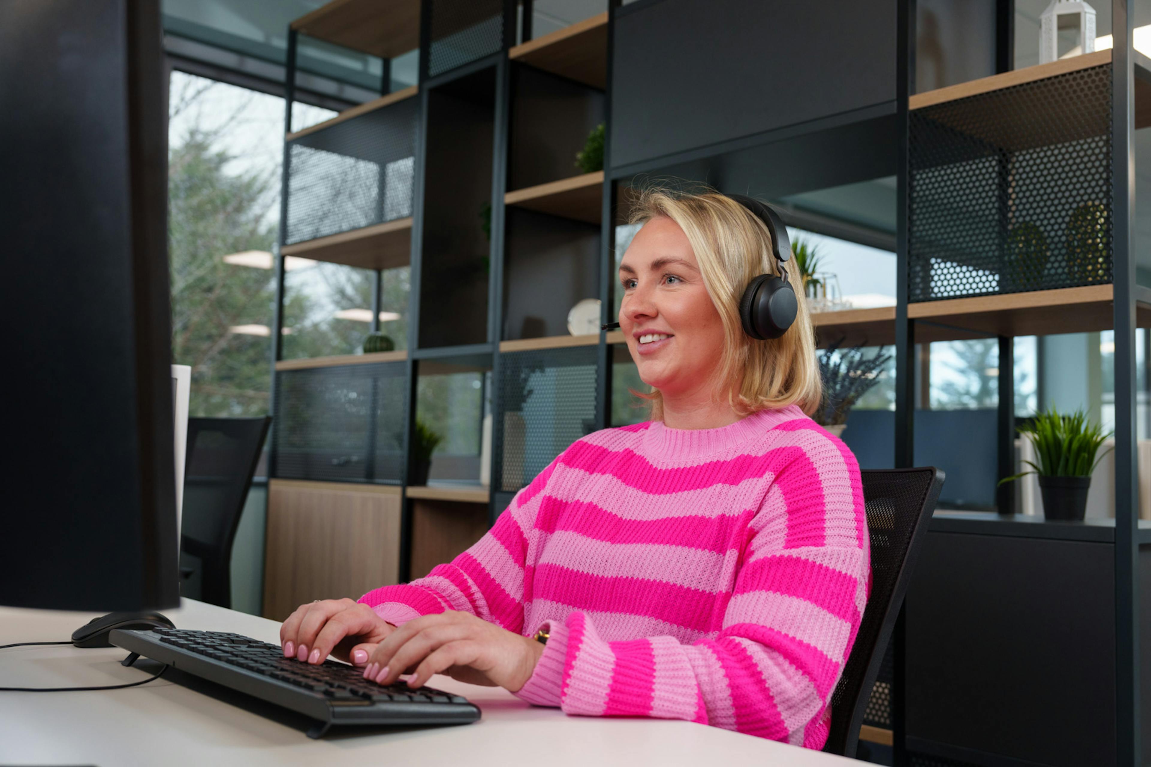 A team member working on a computer with a headset