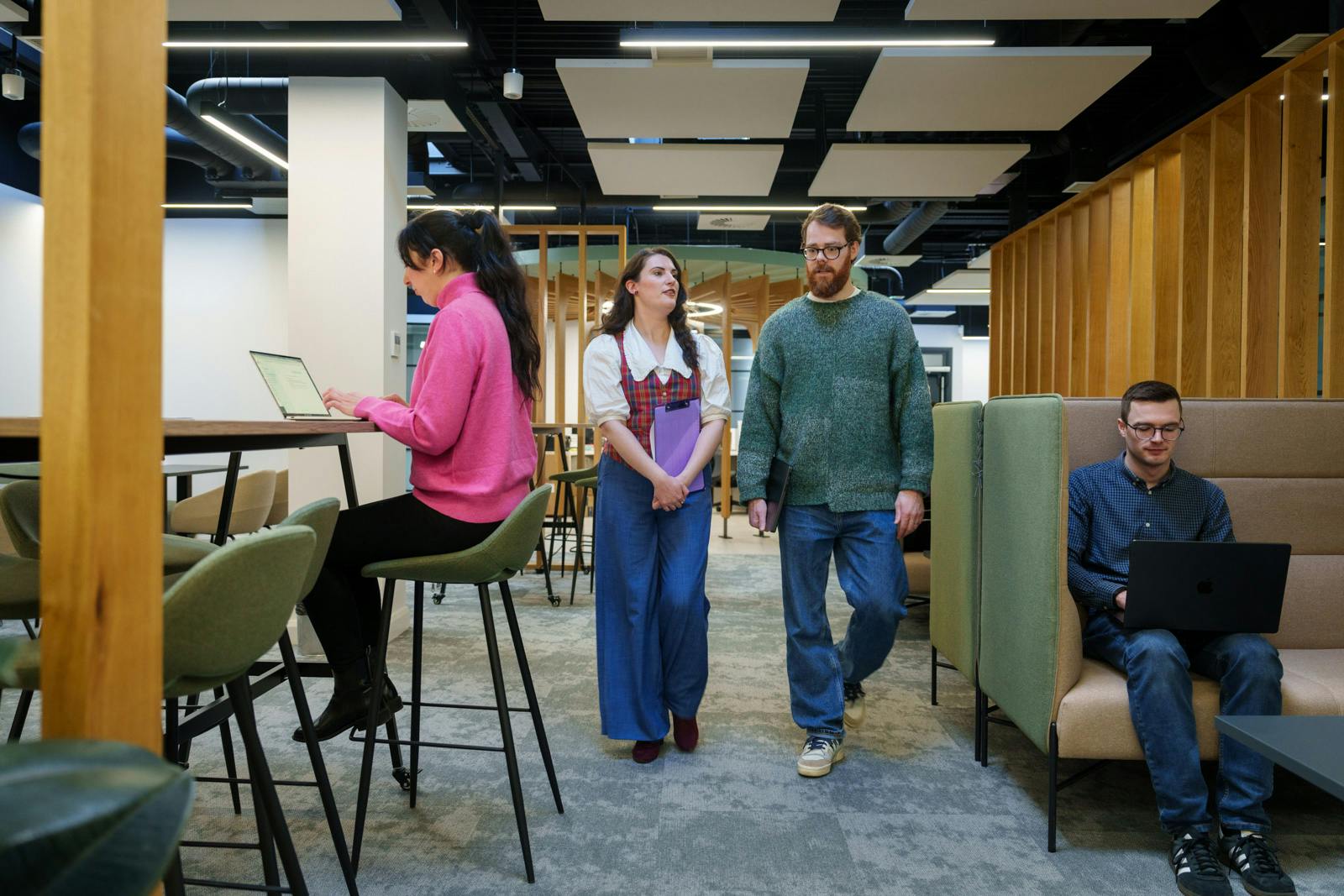 An open office space featuring two team members working and two walking towards the camera