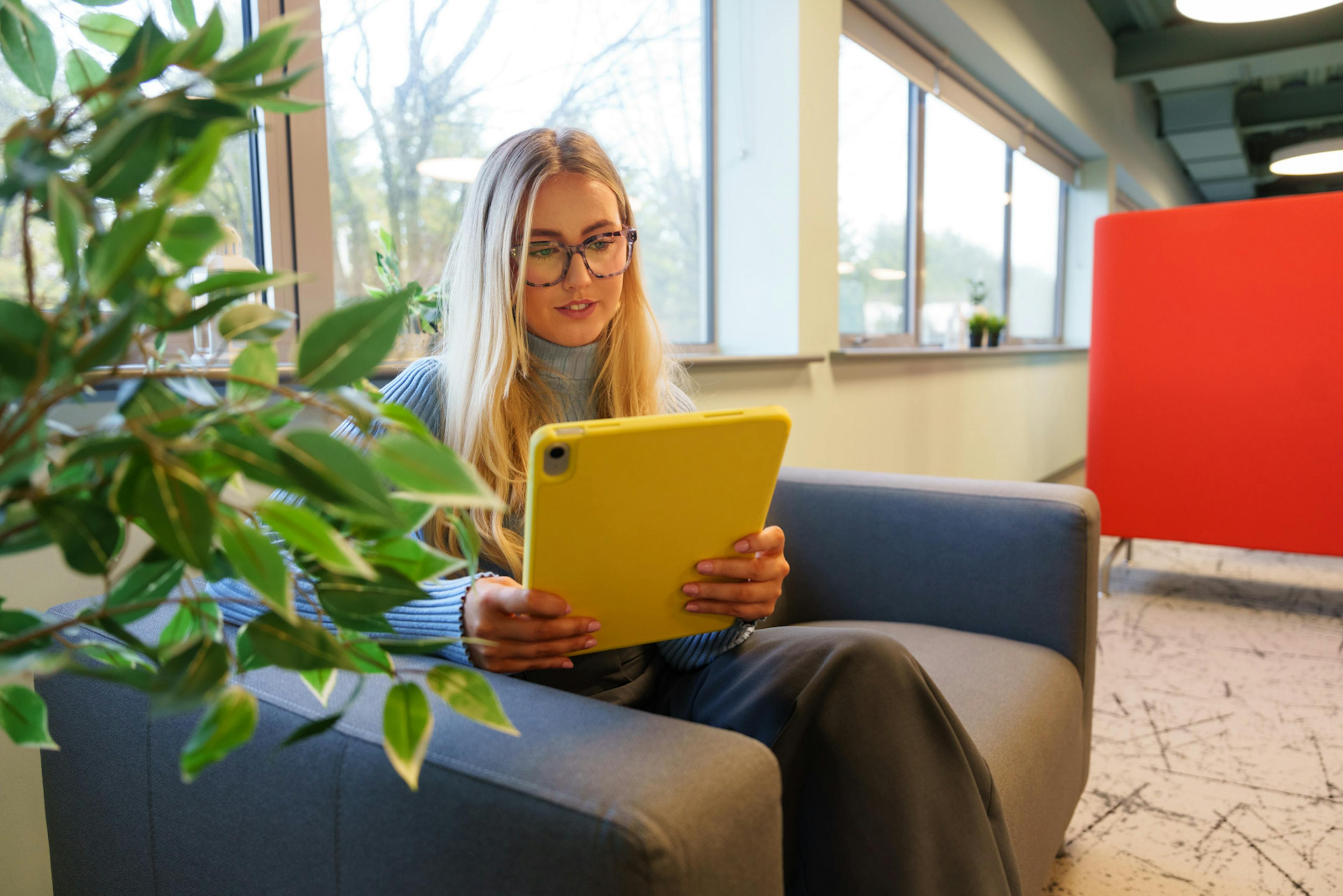 An Everway team member sitting on a sofa looking at an iPad