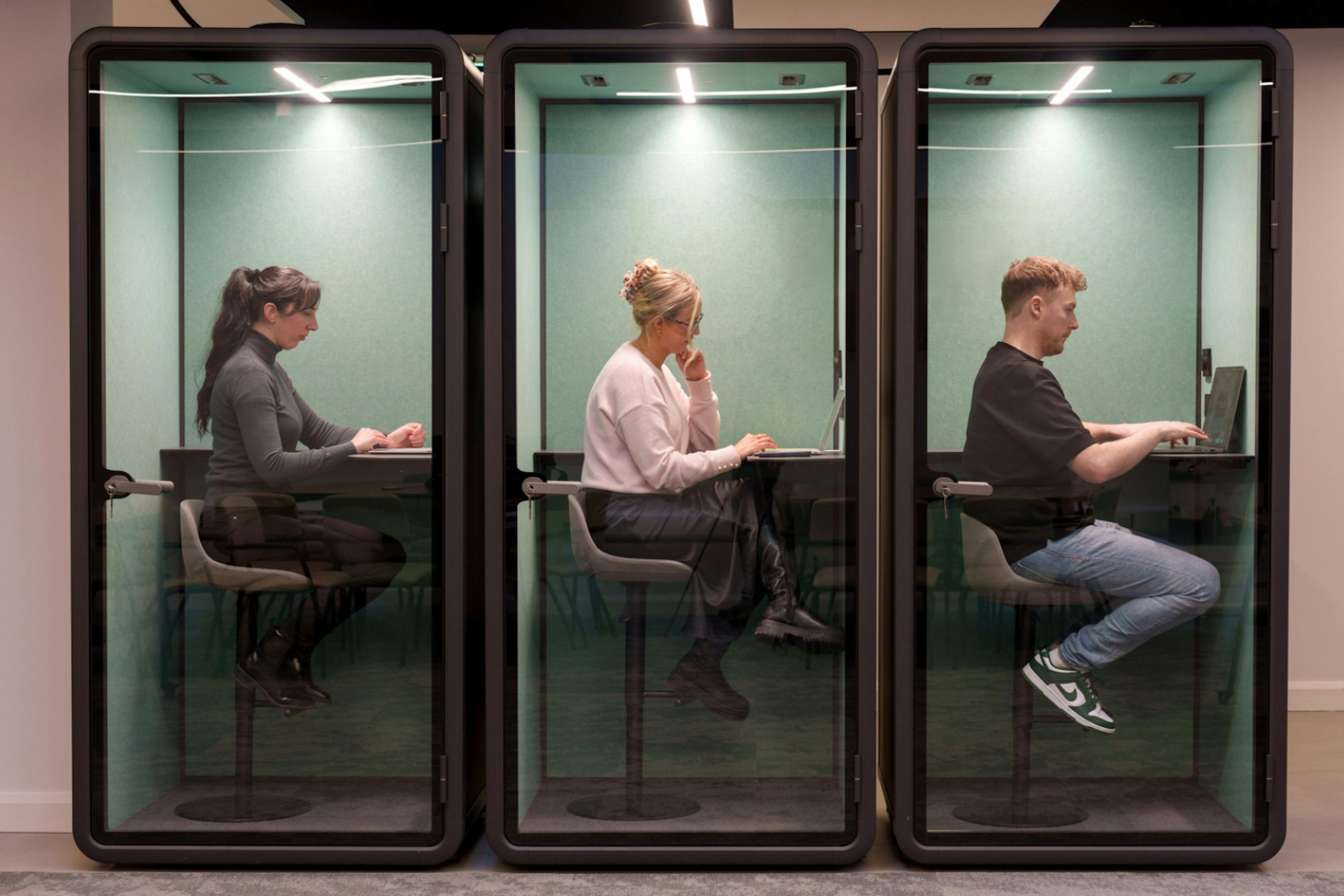 three sound proof booths with people working in them 