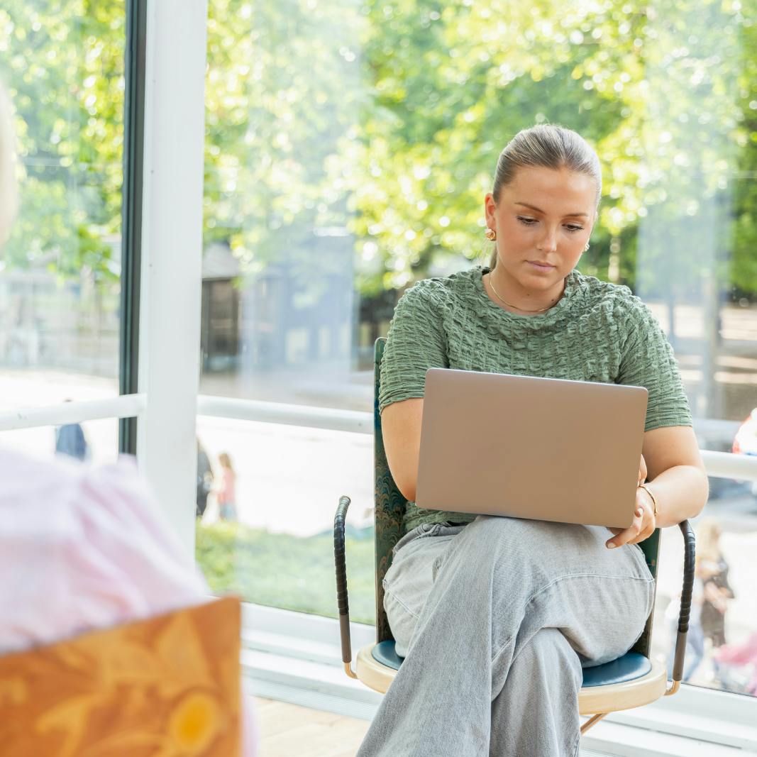 to piger, den ene med en bærbar computer på knæet